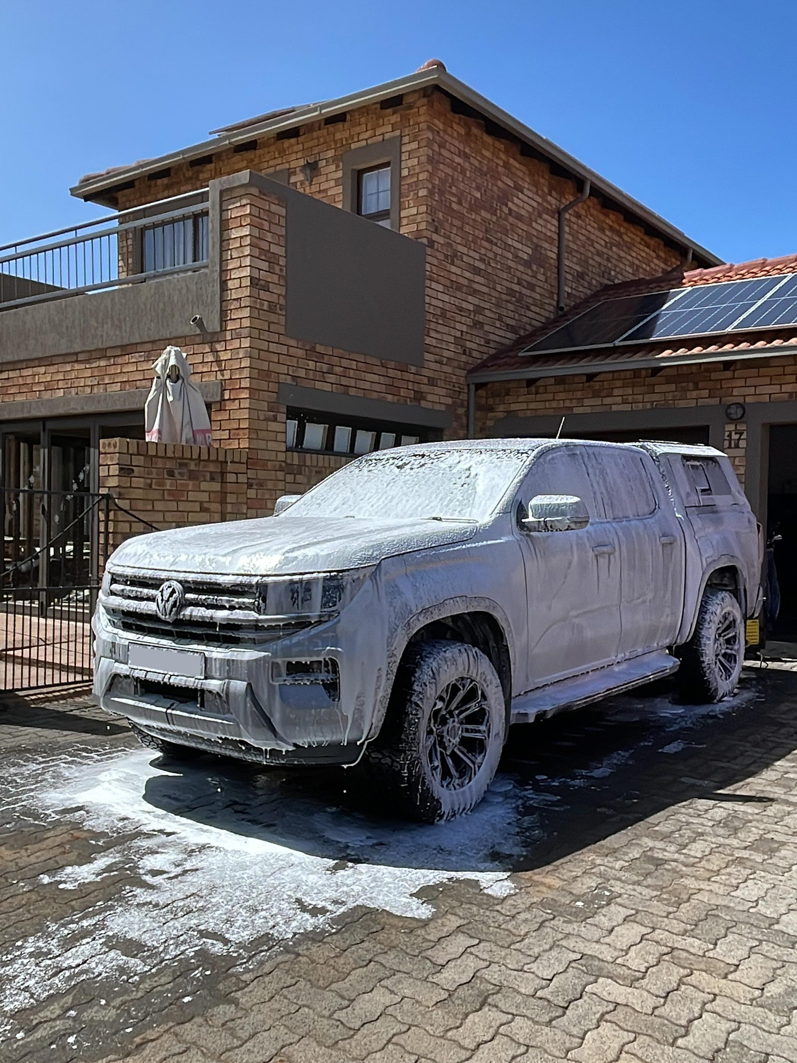 Car exterior being rinsed with a pressure washer after foam wash