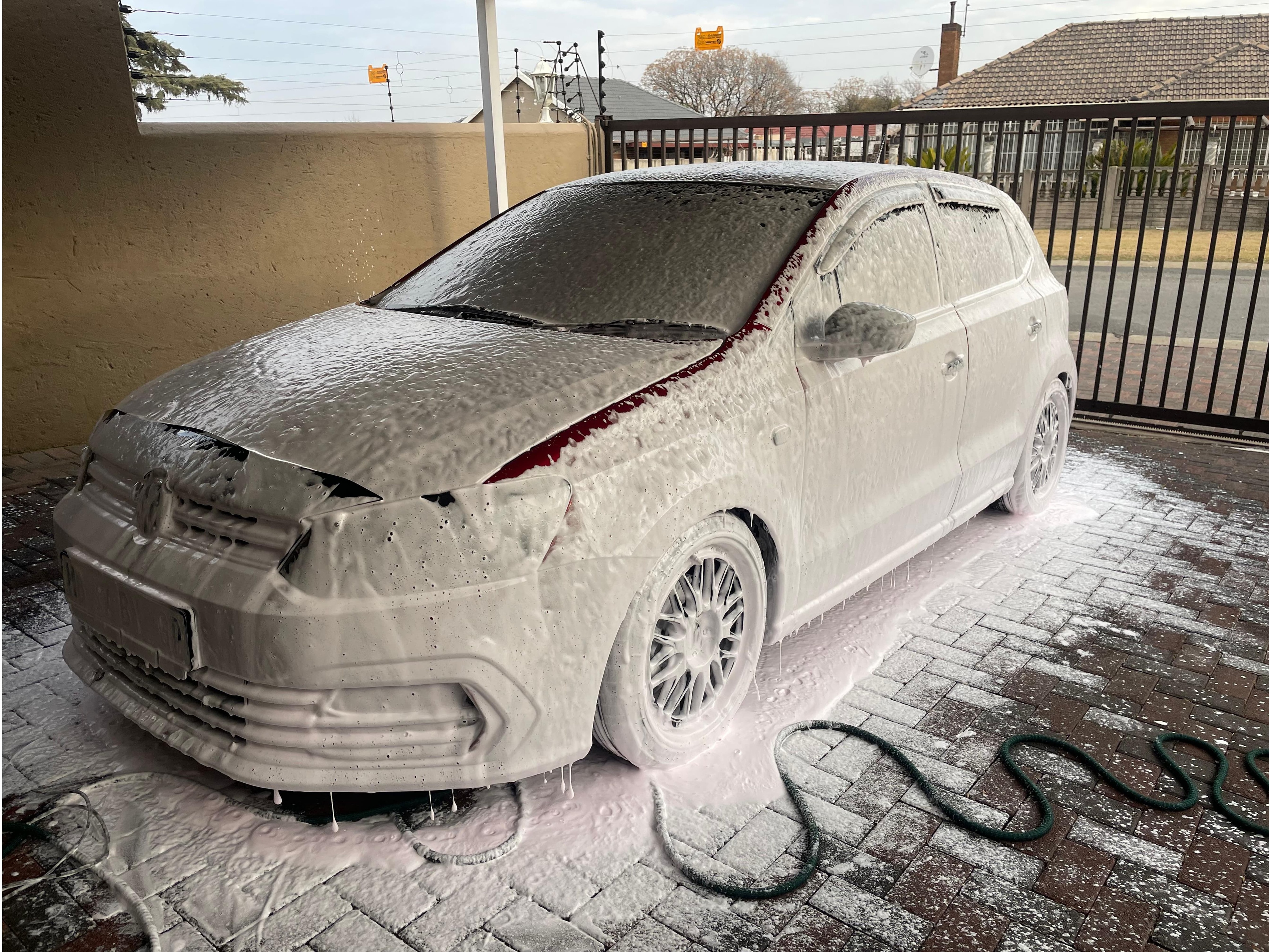 Wide-angle shot of car being foam-washed in a driveway — Basic Wash hero